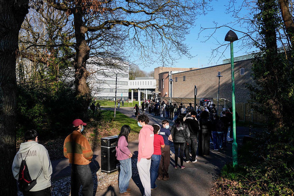 Students wearing face masks queue up to get vaccinated at the University of Kent in Canterbury, south-east England on March 18, 2026,