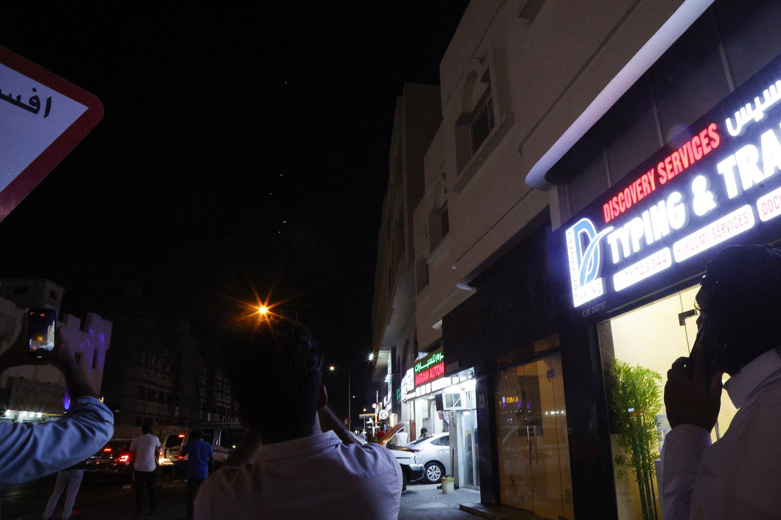  People film projectiles over a street lamp in Doha, Qatar, on June 23
