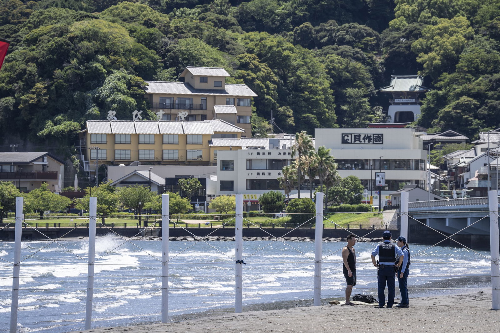 Police officers ask a man to evacuate an empty beach due to a tsunami warning